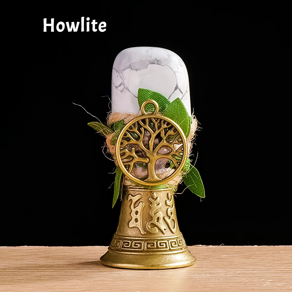A golden chime with a tree of life pendant rests on a white marble stone.