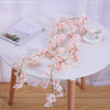 A white table features a pink sakura flower garland and a book, set against a light background.