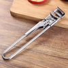 A heavy duty stainless steel bottle opener lying on a wooden cutting board.
