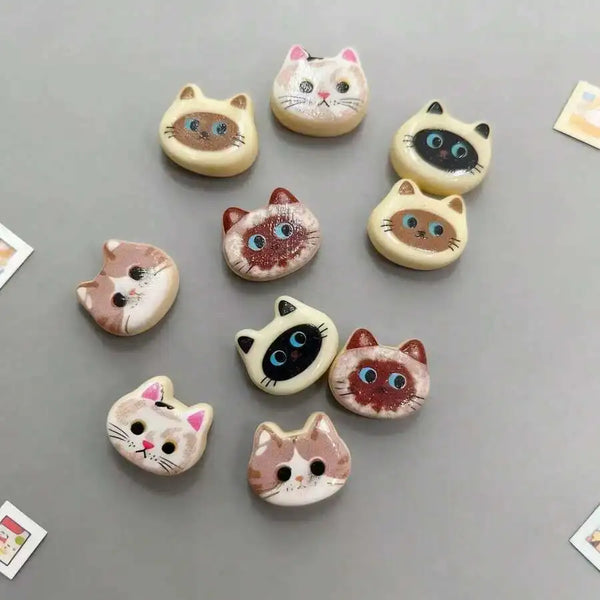 A set of ten adorable cat head fridge magnets in various colors and patterns for kitchen and home decor
