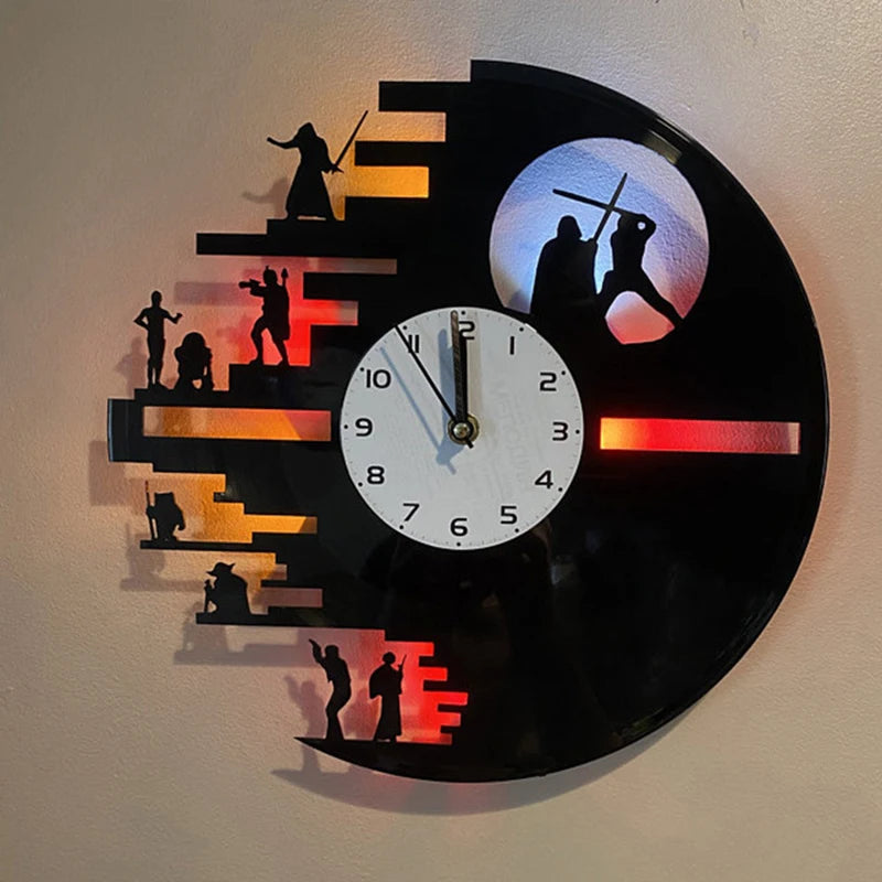 A black vinyl record shaped wall clock features silhouettes of people and a moon, illuminated by orange and red LED lights.