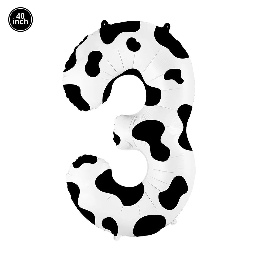 A white foil balloon shaped like the number 3 with black cow print spots.
