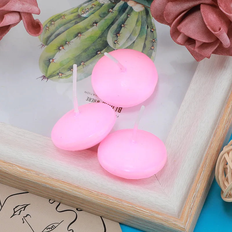 Three pink floating candles displayed in a wooden frame with succulents and rose petals.