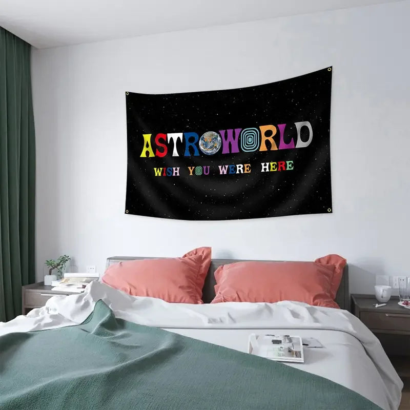 A dark fabric tapestry wall hanging featuring the text ASTROWORLD and WISH YOU WERE HERE in colorful letters against a starry