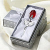 A silver crystal rose artificial flower is displayed in a square box with white lining and a gray patterned lid.