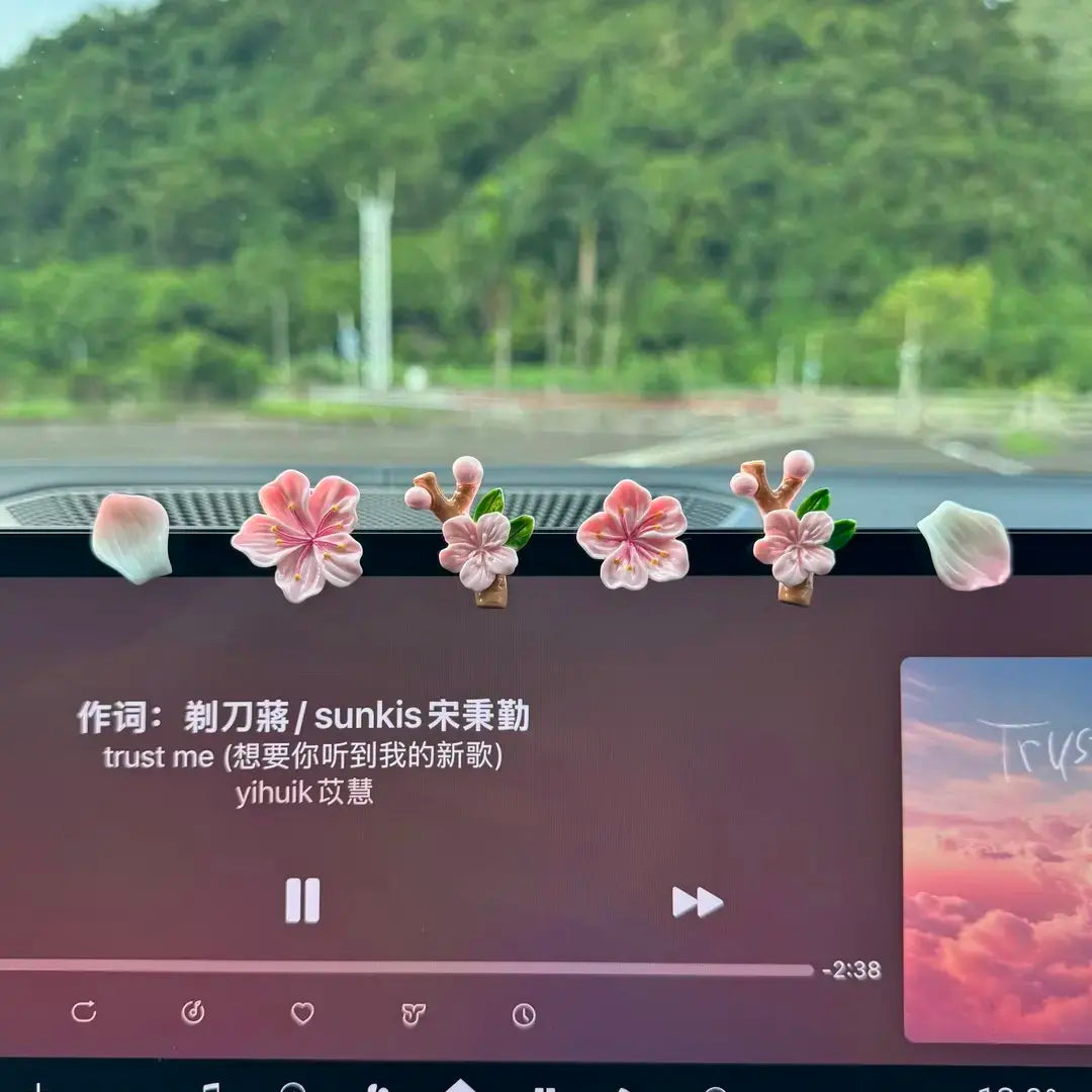 A close-up of a dashboard featuring pink and white 3D peach blossom ornaments.