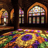 Interior view of a mosque with intricate stained glass windows and colorful floor art.