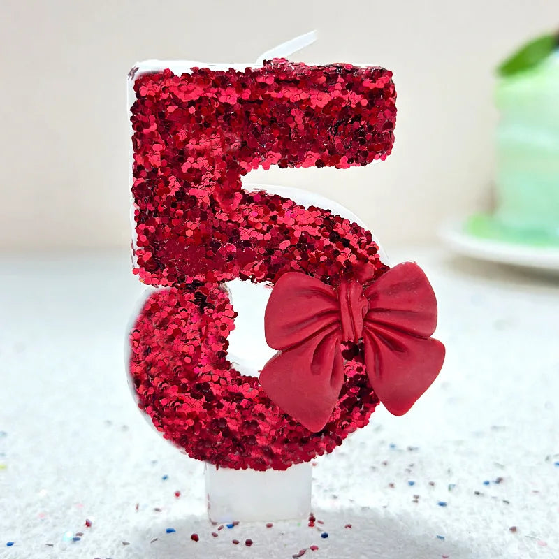 A number five made of red glittery cake frosting and decorated with a large red bow for a birthday celebration.