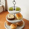 A wooden 3-tier cupcake stand displaying various baked goods including muffins and cupcakes.