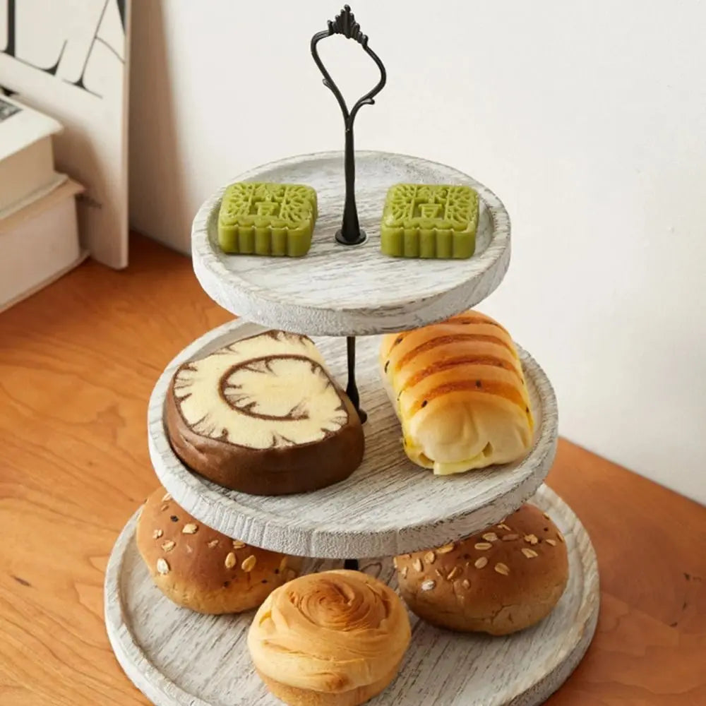 A wooden 3-tier cupcake stand displaying various baked goods including muffins and cupcakes.