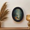 Oval wall art featuring a witch, black cat, and woodland scene in an antique gold frame.