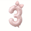Large pink foil number balloon shaped like the number 3 with a bow