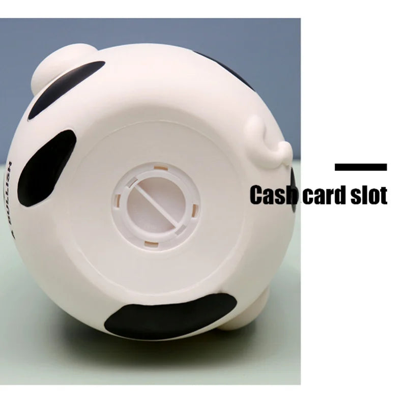 A white and black cow piggy bank with a cash card slot visible on the side.