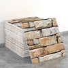 Stacked rectangular marble peel-and-stick tiles with gold accents displayed on a gray surface.