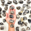 A hand holds several natural raw healing crystal stones for chakra balancing and home decor