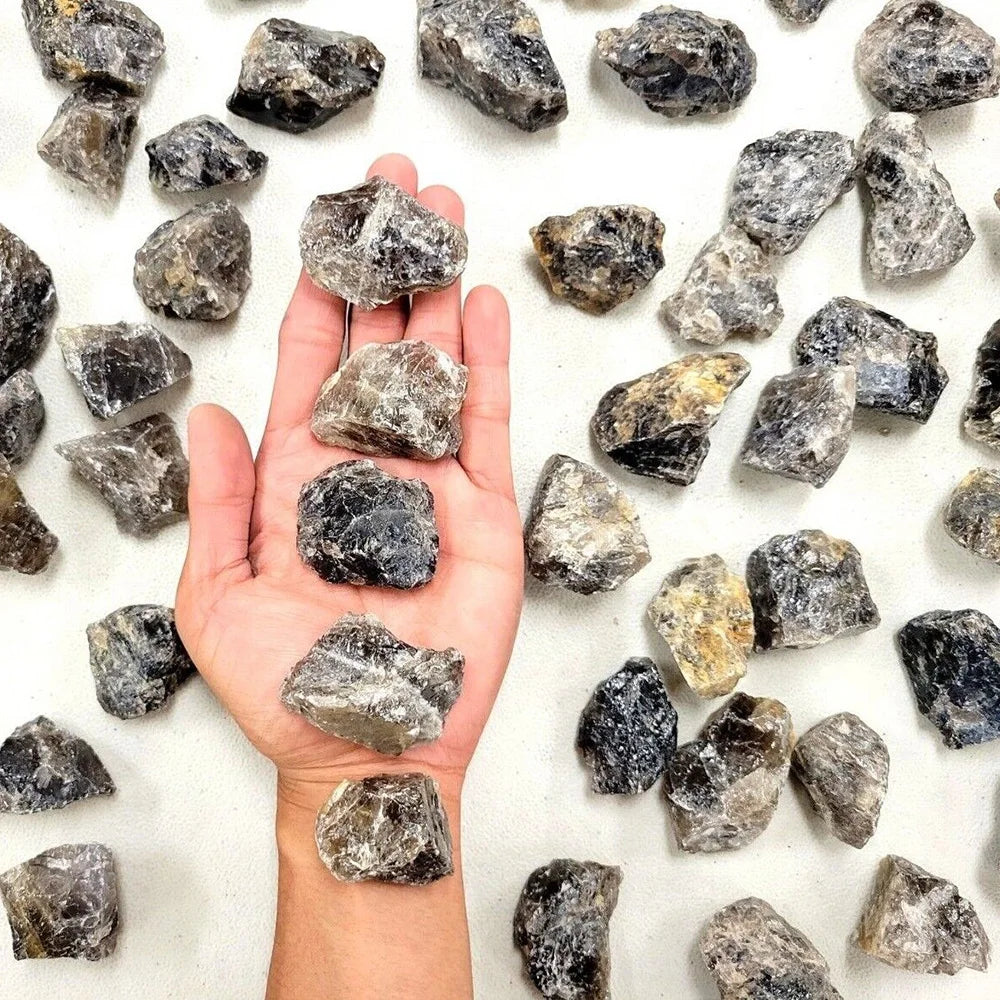 A hand holds several natural raw healing crystal stones for chakra balancing and home decor