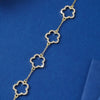 A delicate gold-plated cubic zirconia flower bracelet with a chain and four floral charms displayed against a dark blue backg