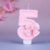 Glittery pink number five birthday candle with a decorative pink bow
