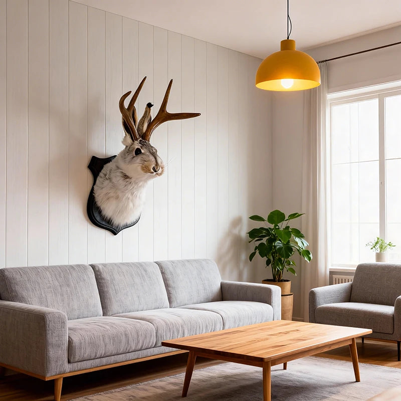 A decorative bunny head mounted on a wall above a modern sofa and wooden coffee table in a bright living room.