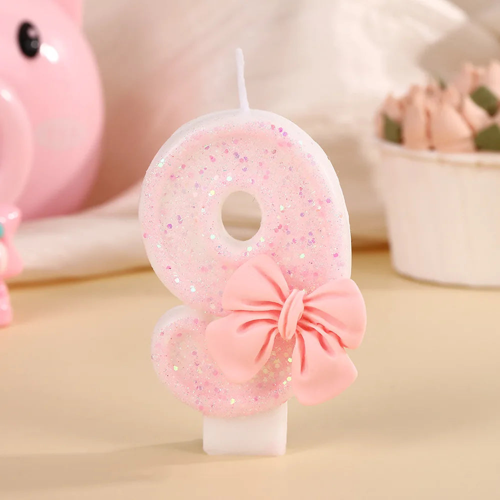 A pink glitter candle shaped like the number 8 with a pink bow, displayed on a light background.