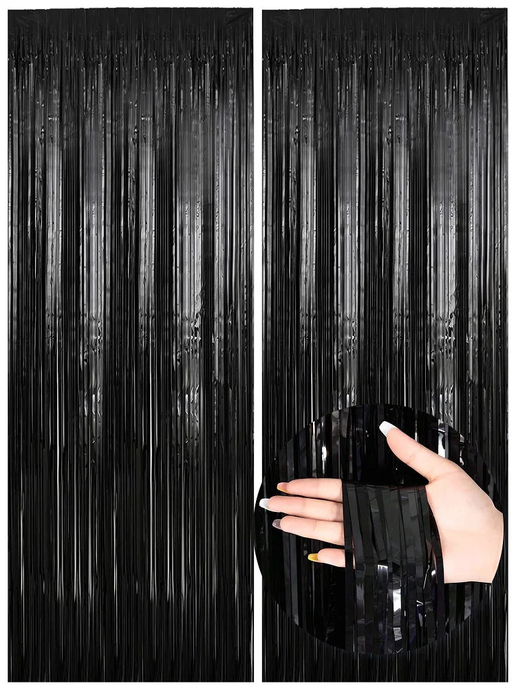 A hand reaches through black metallic foil fringe curtains, showing the texture and drape of the fabric.