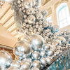 A close-up of metallic gold and silver balloons arranged in a dense, cascading display for party decorations.