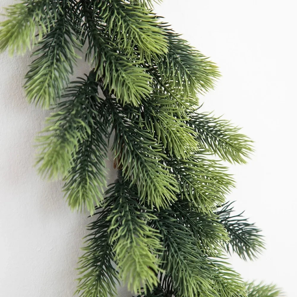 A long, green artificial pine garland draped against a white background.