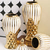 Two handcrafted ceramic decorative vases in gold and white stripes with a small lid.