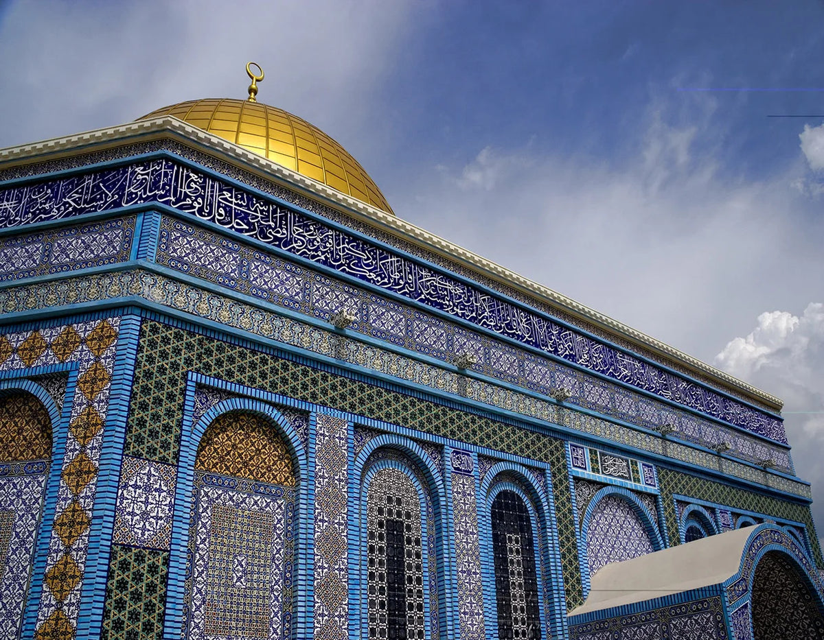A close-up of an Islamic mosque dome and facade featuring intricate blue, gold, and green tilework.