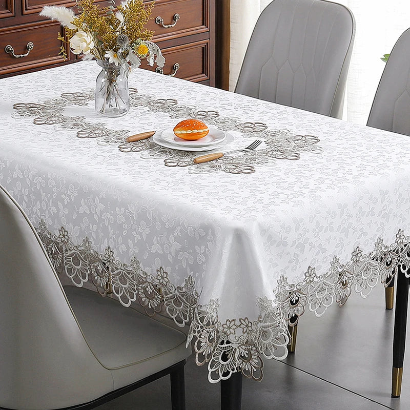 White tablecloth with silver lace trim and floral pattern set on a dining table.