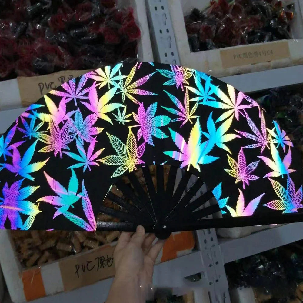 A black folding bamboo hand fan with neon light accents is displayed against a background of other decorative items.