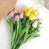 A bouquet of artificial tulips in shades of pink, yellow, and white arranged on a white surface.