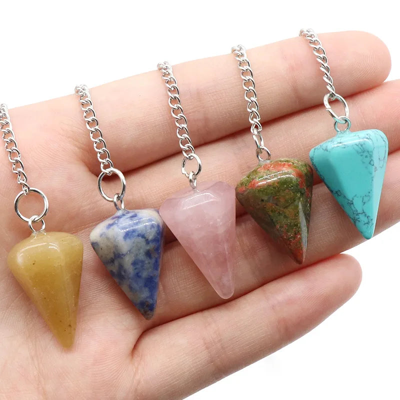 A hand displays five natural stone pendants with silver chains and various colors including yellow, blue, pink, green, and tu