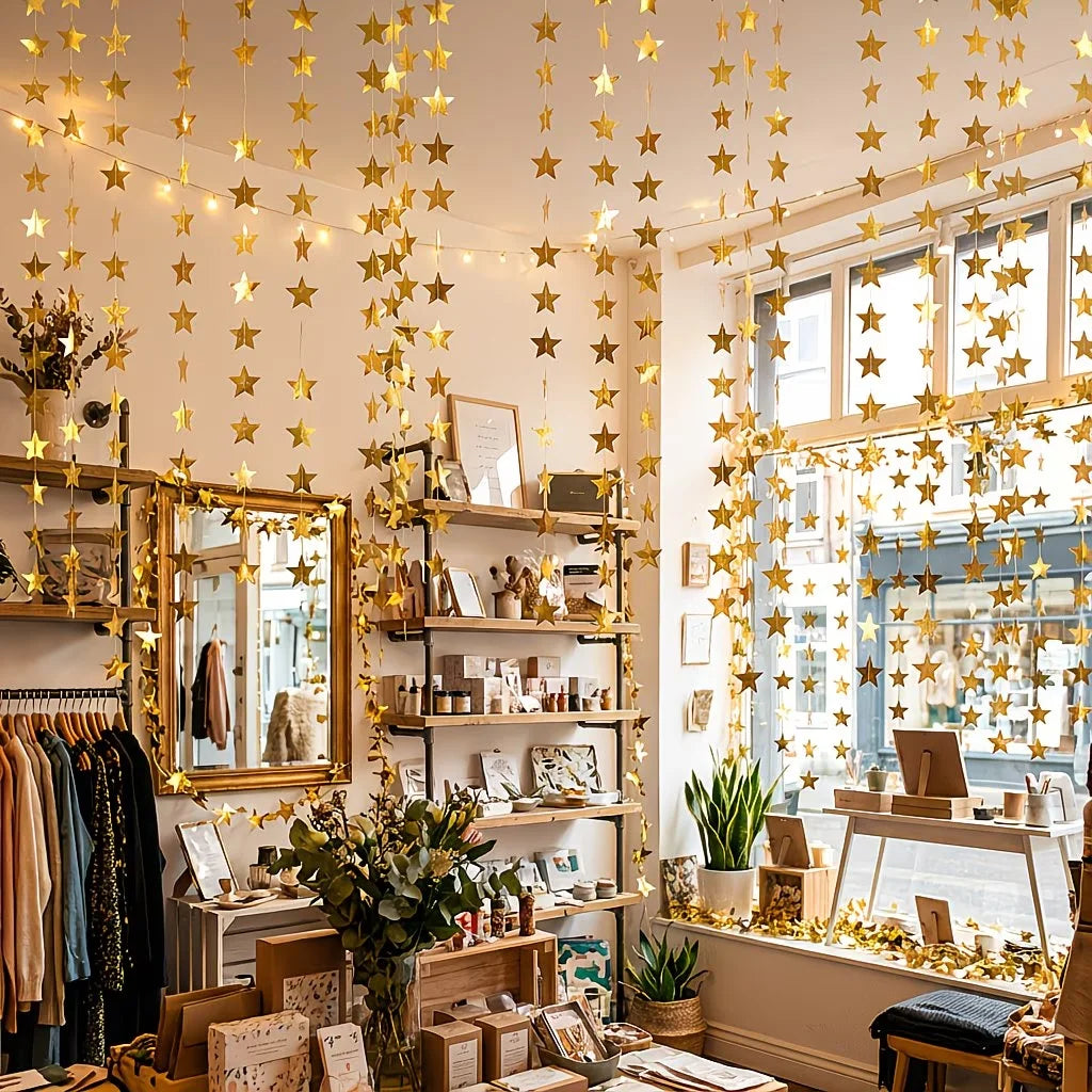 A display of shimmering gold and silver star paper garlands and bunting hanging in a bright shop setting.