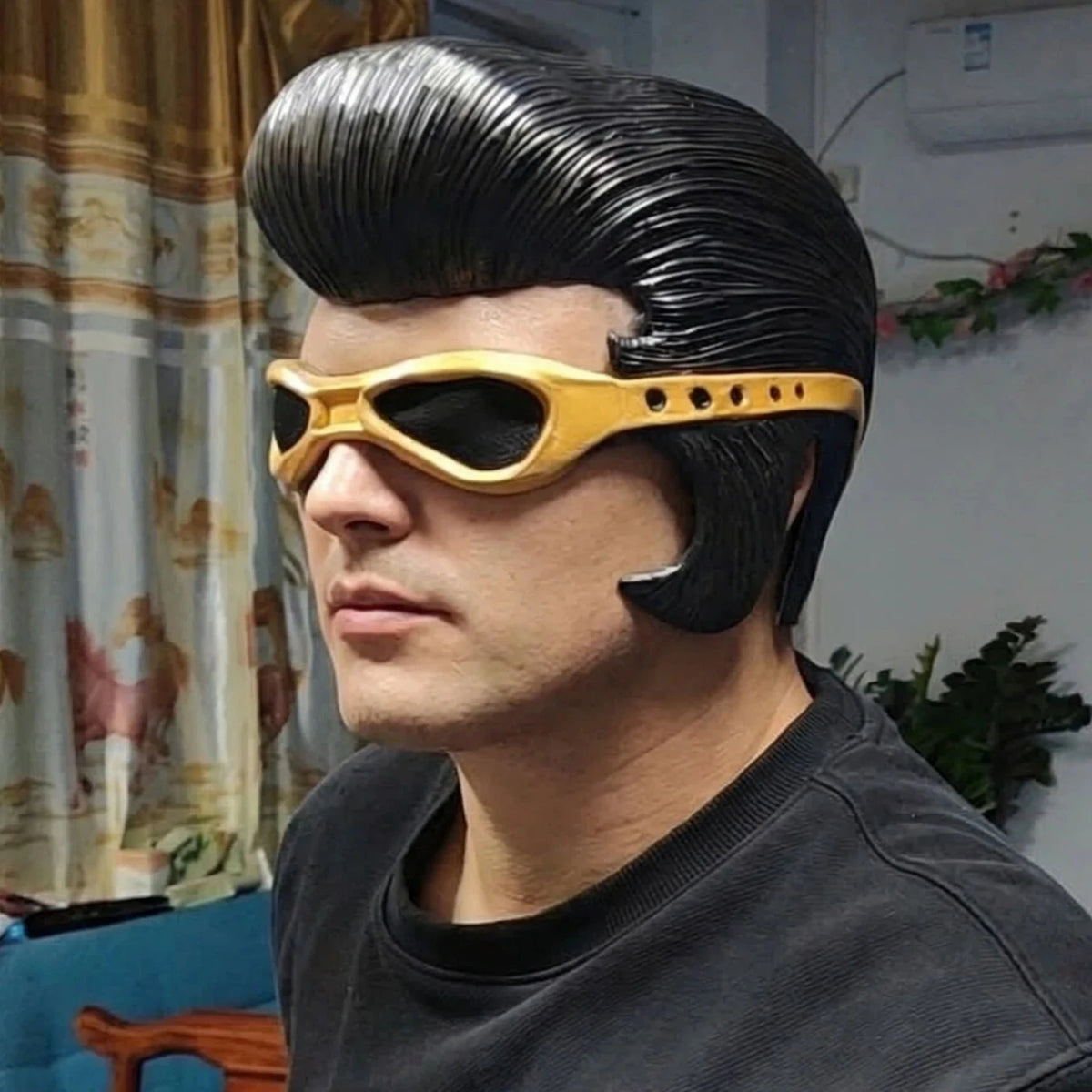 Un hombre con peinado mohawk negro y gafas de sol vintage doradas.