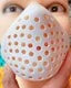 A hand is holding a realistic horror animal mask for Halloween costumes with small holes visible on the surface.