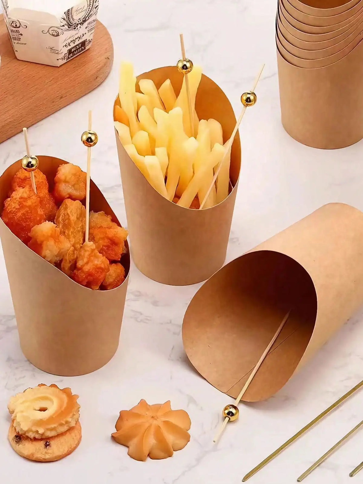 A collection of disposable kraft paper serving cups filled with french fries and fried food items.
