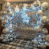 A silver and white balloon arch backdrop with a sparkling glitter square wall texture.