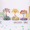 A display of natural chakra healing crystal trees in various colors on a white wooden box.