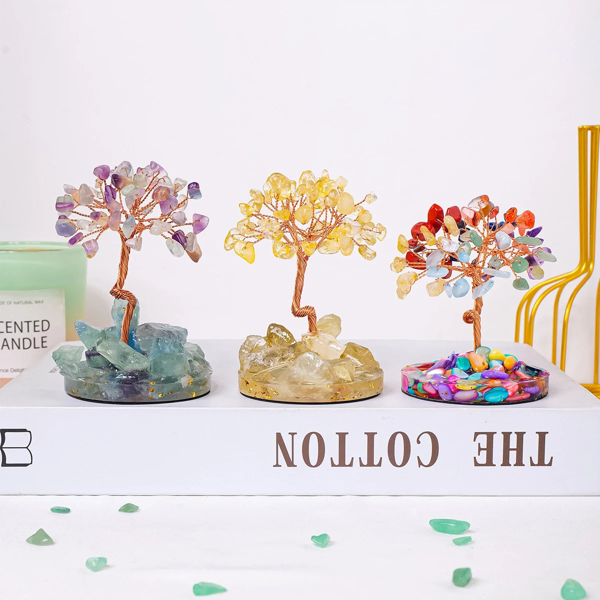 A display of natural chakra healing crystal trees in various colors on a white wooden box.