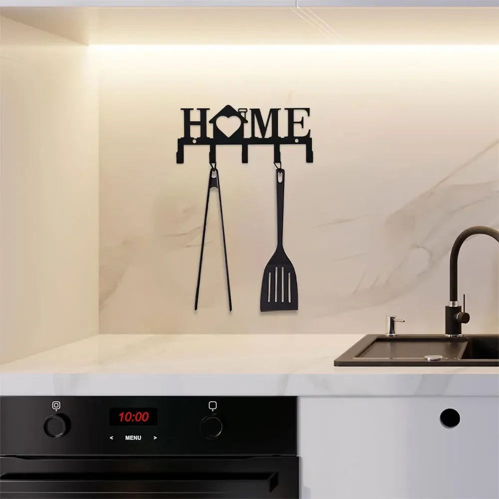 A black wall key holder with hooks is mounted above a kitchen countertop and sink area.