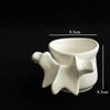 A white ceramic vase shaped like a vertebra, photographed against a black background.