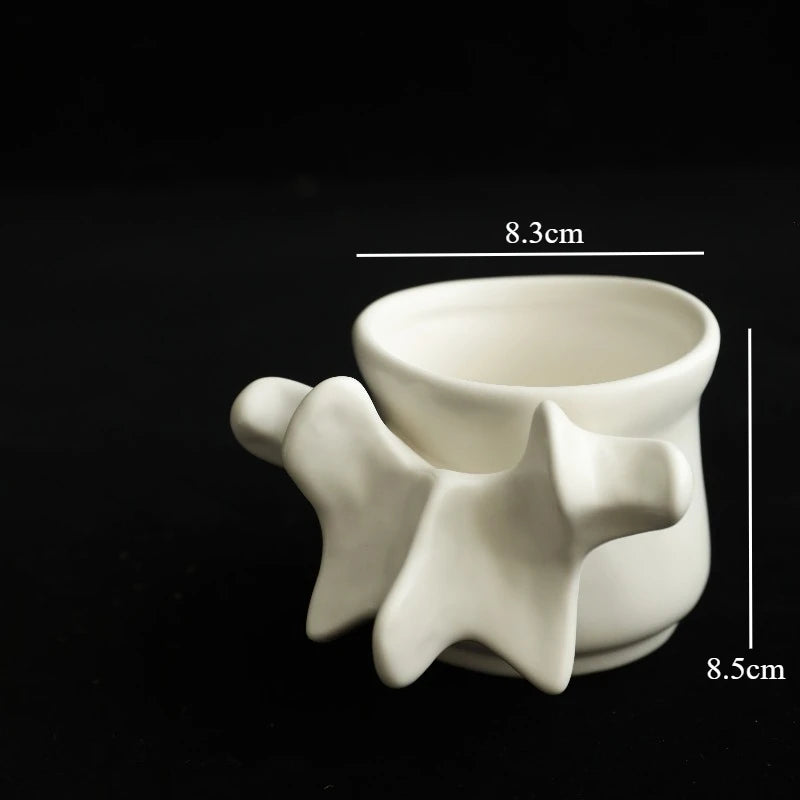 A white ceramic vase shaped like a vertebra, photographed against a black background.
