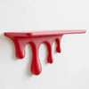 A red acrylic drip floating shelf with an artistic, dripping texture mounted on a white wall.