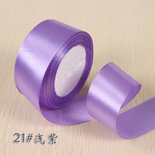 A roll of purple silk satin ribbon used for gift wrapping and craft projects.