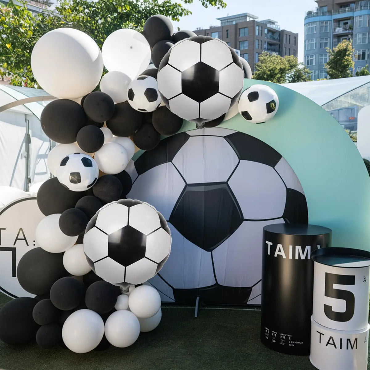 A balloon garland arch decoration featuring black and white soccer balls in a large, curved display.