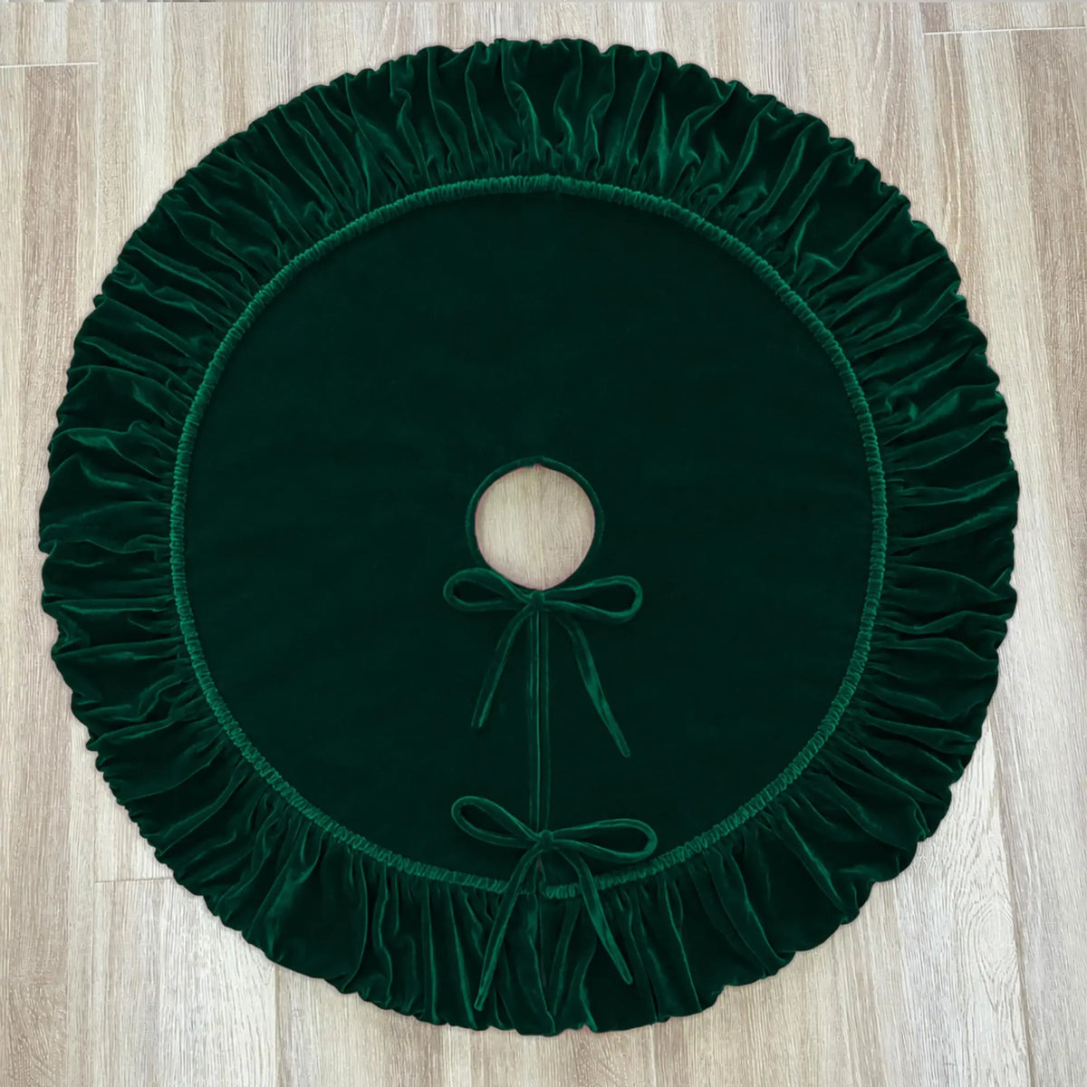Dark green velvet Christmas tree skirt with a ruffled edge and a circular opening