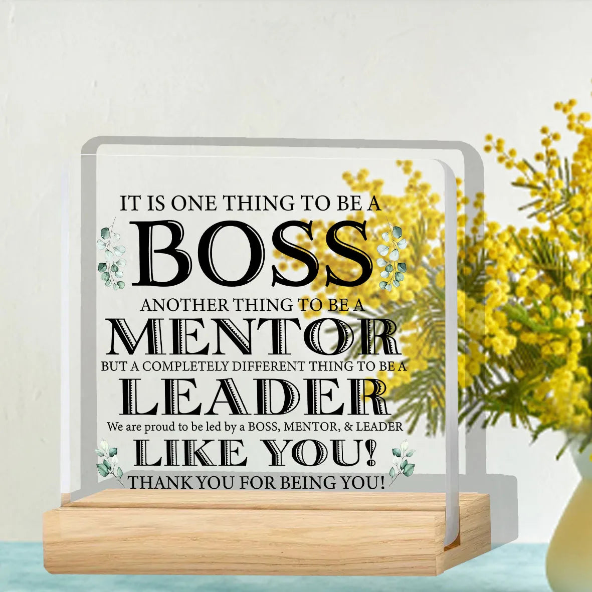 A clear acrylic plaque with text appreciating a boss, mentor, and leader, set on a wooden base.