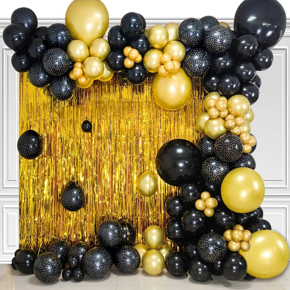 A dense arrangement of black and gold latex balloons forming a decorative backdrop.
