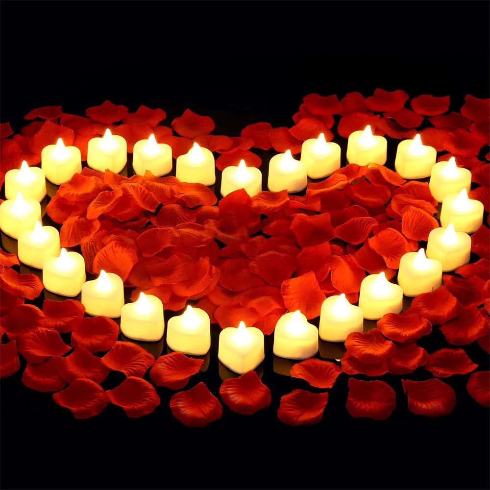 Forme de cœur faite de bougies blanches lumineuses entourées de pétales de roses rouges artificielles.